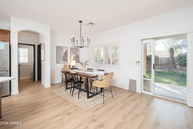 dining space with light hardwood / wood-style floors and a notable chandelier