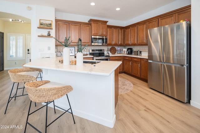 kitchen featuring appliances with stainless steel finishes, a kitchen bar, light wood-type flooring, and kitchen peninsula