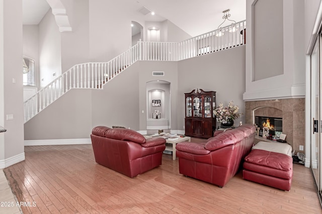 living area with arched walkways, baseboards, light wood-style flooring, and stairway