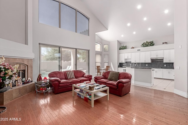 living room featuring high vaulted ceiling, a premium fireplace, and light wood-type flooring