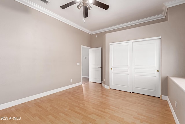 unfurnished bedroom with crown molding, baseboards, and light wood-type flooring