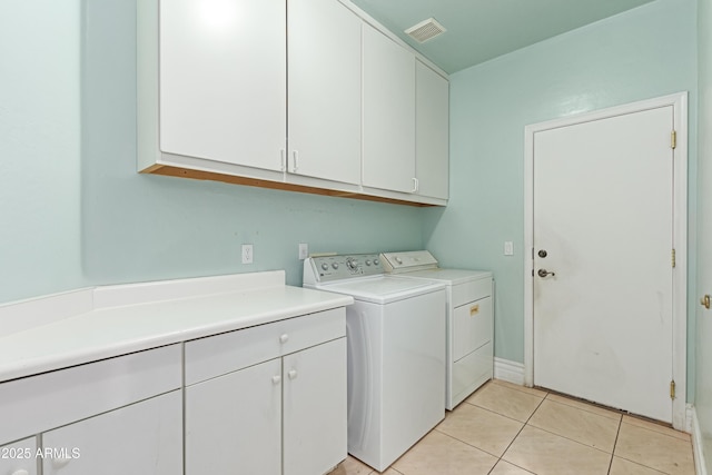 laundry room with light tile patterned floors, cabinet space, washing machine and dryer, and visible vents
