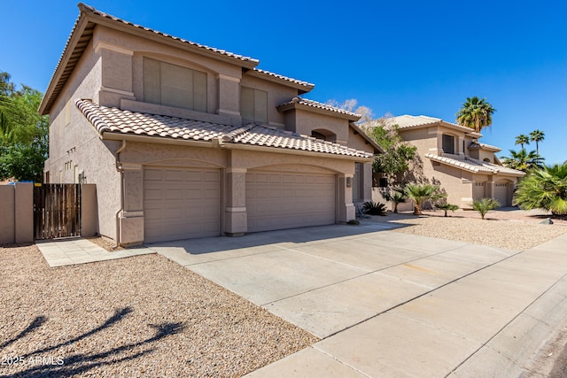 mediterranean / spanish home featuring driveway, stucco siding, a gate, and a tiled roof