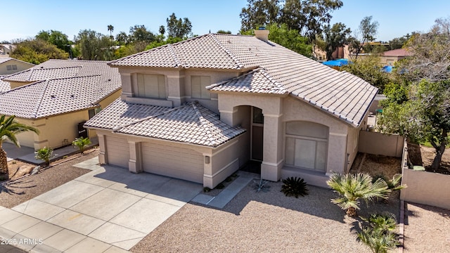 mediterranean / spanish-style house with stucco siding, driveway, a garage, and a tiled roof