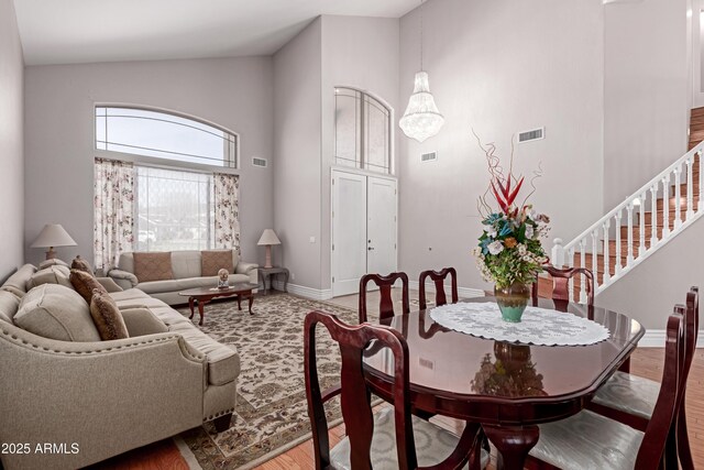 living room with wood finished floors, a towering ceiling, baseboards, and visible vents