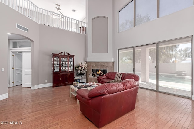living room featuring arched walkways, visible vents, a glass covered fireplace, and light wood-style floors