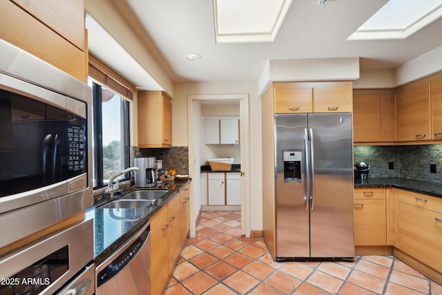 kitchen featuring light tile patterned floors, stainless steel appliances, a sink, and decorative backsplash