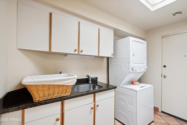 washroom with light tile patterned flooring, stacked washer / dryer, a sink, visible vents, and cabinet space