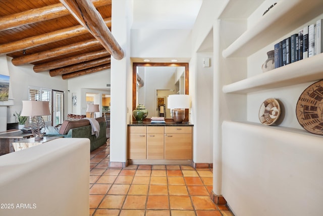 hall with vaulted ceiling with beams, wooden ceiling, and light tile patterned floors