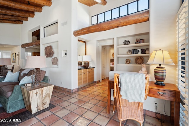 interior space featuring light tile patterned floors, a high ceiling, open floor plan, beamed ceiling, and baseboards