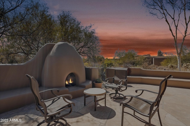 view of patio featuring a warm lit fireplace