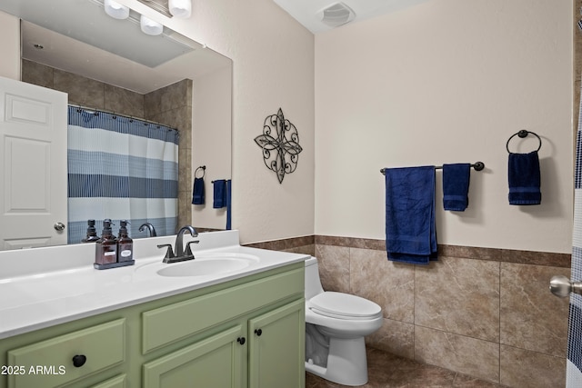 bathroom with tile patterned floors, toilet, curtained shower, tile walls, and vanity