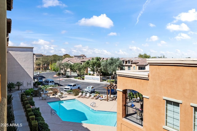 pool with a patio area, fence, and a residential view