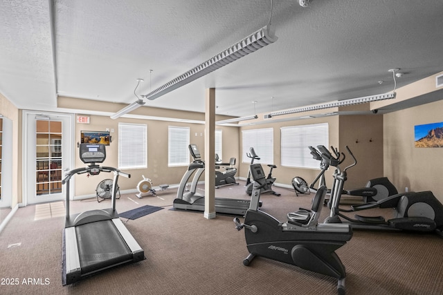 gym featuring a textured ceiling and baseboards