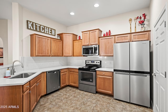 kitchen featuring light countertops, recessed lighting, brown cabinetry, stainless steel appliances, and a sink