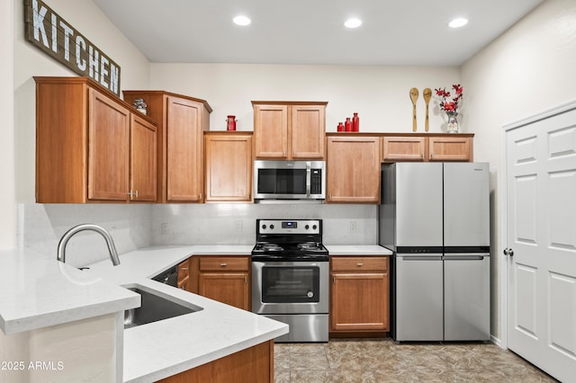 kitchen featuring a sink, stainless steel appliances, brown cabinets, and a peninsula