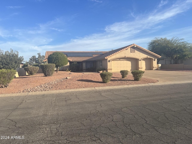 mediterranean / spanish house featuring a garage, concrete driveway, a tiled roof, and stucco siding