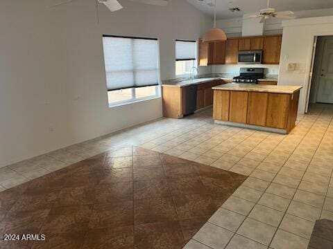 kitchen with ceiling fan, a kitchen island, stainless steel microwave, stove, and light countertops