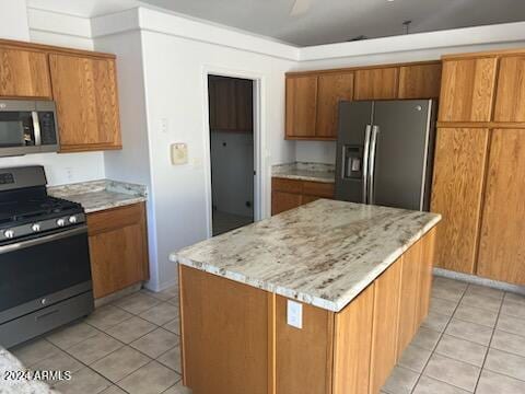 kitchen with appliances with stainless steel finishes, brown cabinetry, and a kitchen island