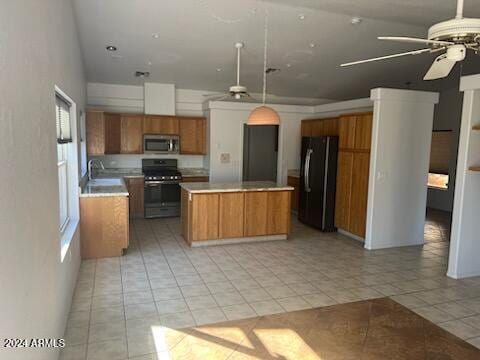 kitchen with a center island, light countertops, appliances with stainless steel finishes, brown cabinetry, and light tile patterned flooring