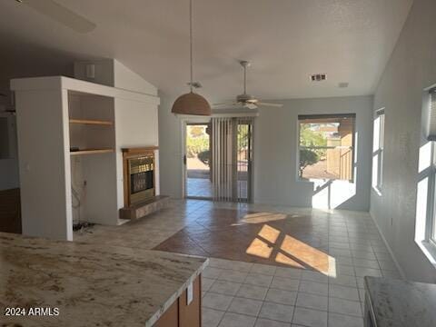 unfurnished living room with vaulted ceiling, light tile patterned flooring, a glass covered fireplace, and a ceiling fan