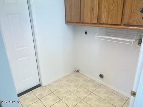 clothes washing area featuring cabinet space, baseboards, electric dryer hookup, and light tile patterned flooring