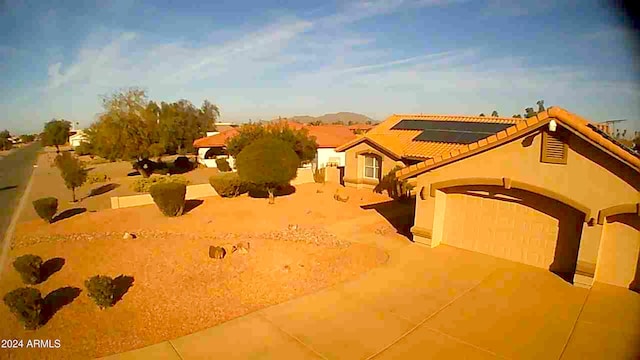 view of front facade with a garage, concrete driveway, and roof mounted solar panels