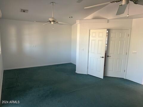 empty room featuring ceiling fan, visible vents, and dark carpet