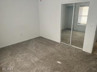 unfurnished bedroom featuring dark colored carpet and a closet