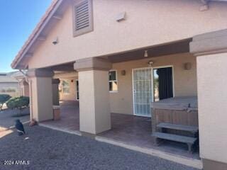 back of property featuring a patio area, a jacuzzi, and stucco siding