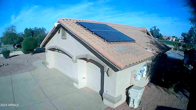 view of property exterior with stucco siding, a tile roof, and solar panels