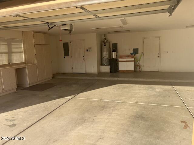 garage featuring electric panel, water heater, and a garage door opener