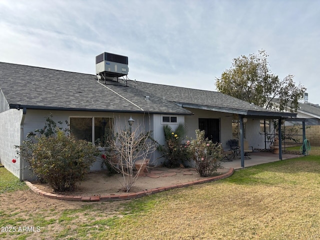 rear view of property with central AC, a yard, roof with shingles, and a patio area