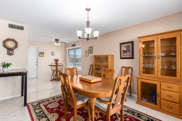 tiled dining room featuring ceiling fan with notable chandelier