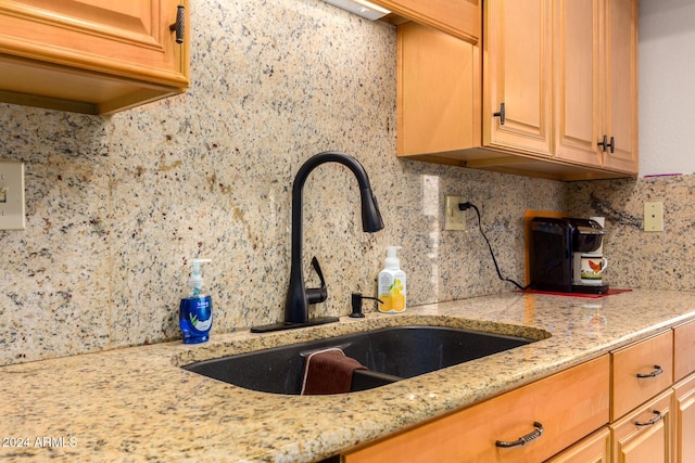 kitchen featuring sink, light stone countertops, and backsplash