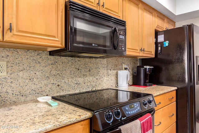 kitchen featuring black appliances, light stone countertops, and tasteful backsplash