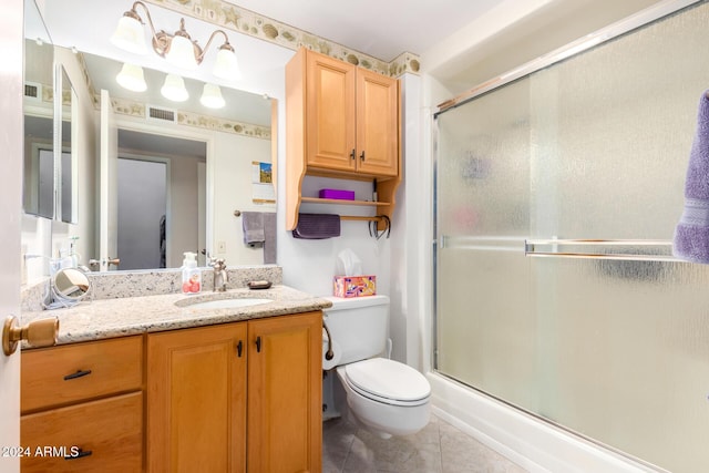 bathroom featuring tile patterned flooring, vanity, a shower with shower door, and toilet