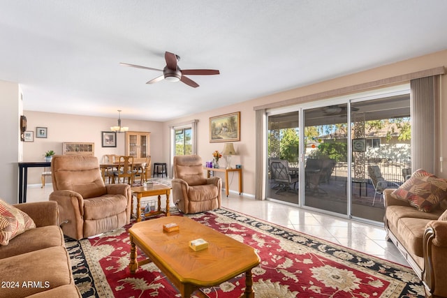 tiled living room featuring ceiling fan with notable chandelier