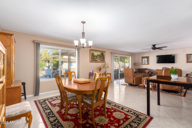 tiled dining room with ceiling fan with notable chandelier