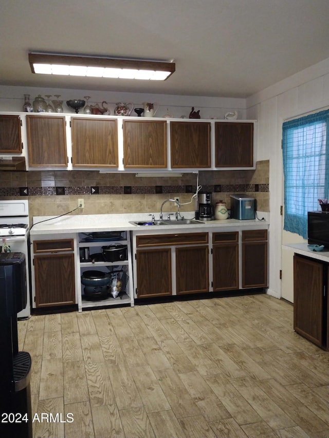 kitchen featuring backsplash, white range, sink, and light hardwood / wood-style flooring