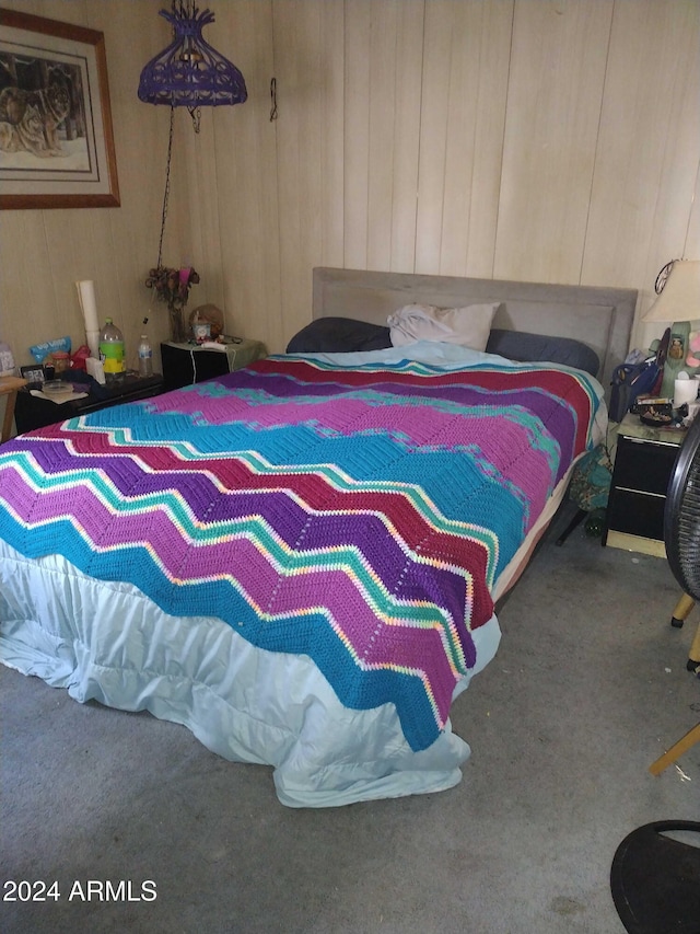 bedroom with carpet flooring and wood walls