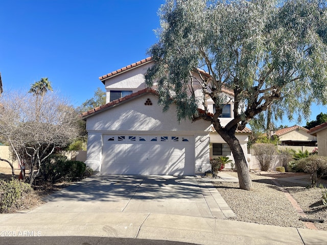 mediterranean / spanish-style house featuring driveway, a tile roof, an attached garage, and stucco siding