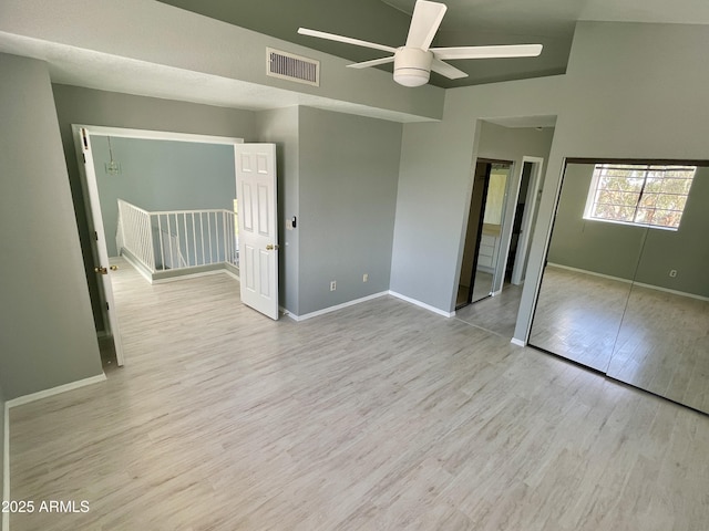 unfurnished bedroom featuring lofted ceiling, a closet, ceiling fan, and light wood-type flooring