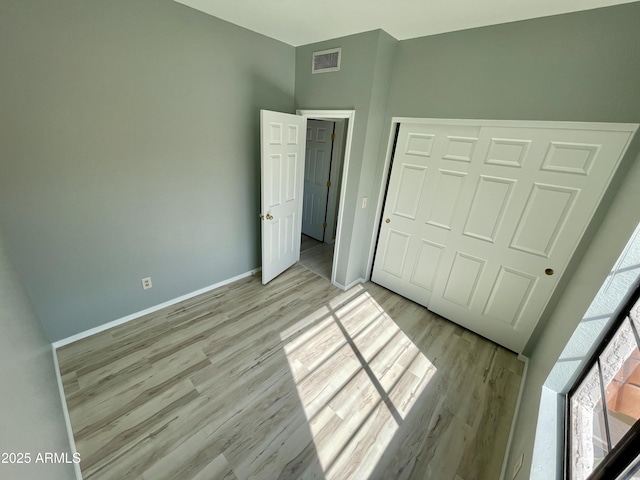 unfurnished bedroom with a closet and light wood-type flooring