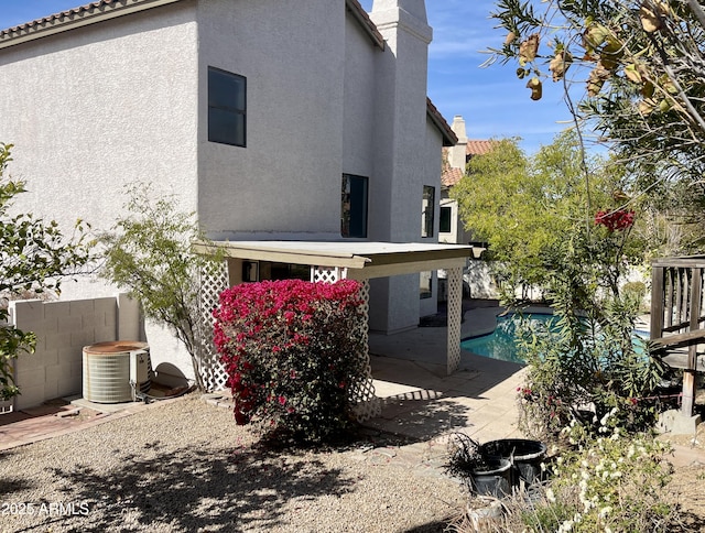 back of house featuring cooling unit, a pool, and a patio area