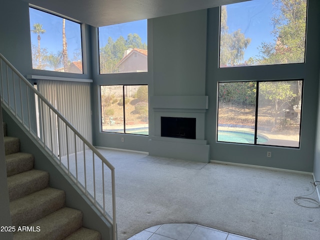 unfurnished living room featuring a high ceiling, a large fireplace, and light carpet