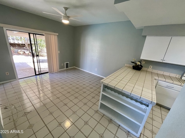 kitchen with ceiling fan, tile counters, and white cabinets