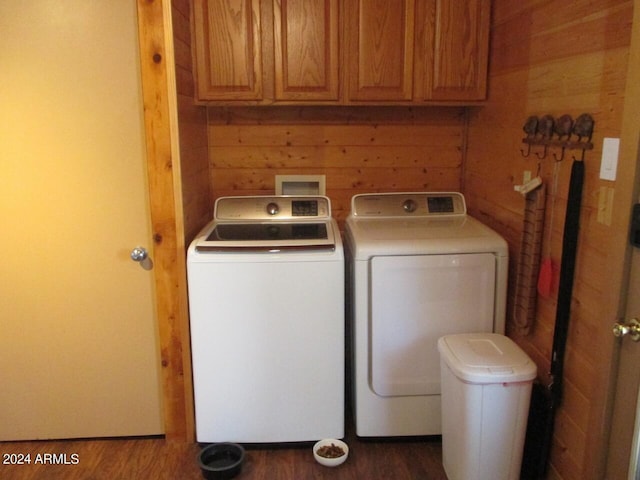 laundry area featuring wood walls, cabinet space, dark wood-type flooring, and washer and dryer