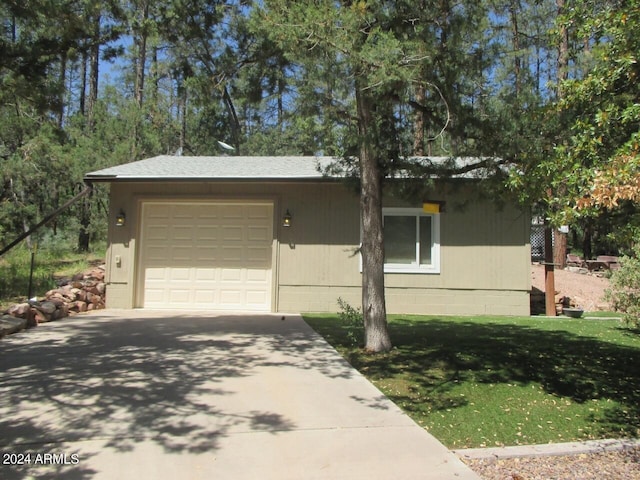 view of front of property with a garage, concrete driveway, roof with shingles, and a front yard