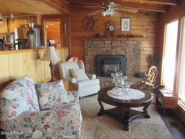 living area featuring a stone fireplace, wooden walls, wood ceiling, visible vents, and beamed ceiling